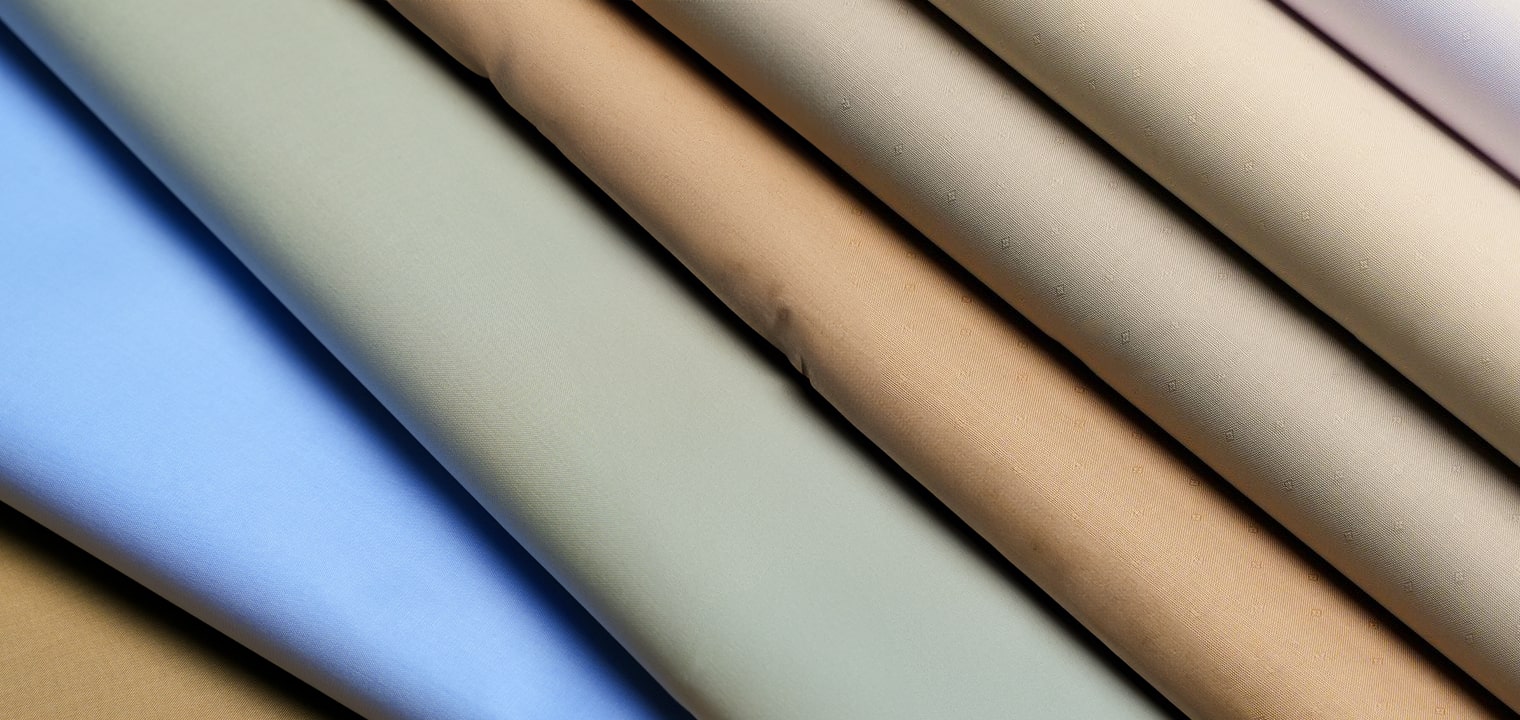 A palette of folded fabrics in blue, sage, camel and neutral shades