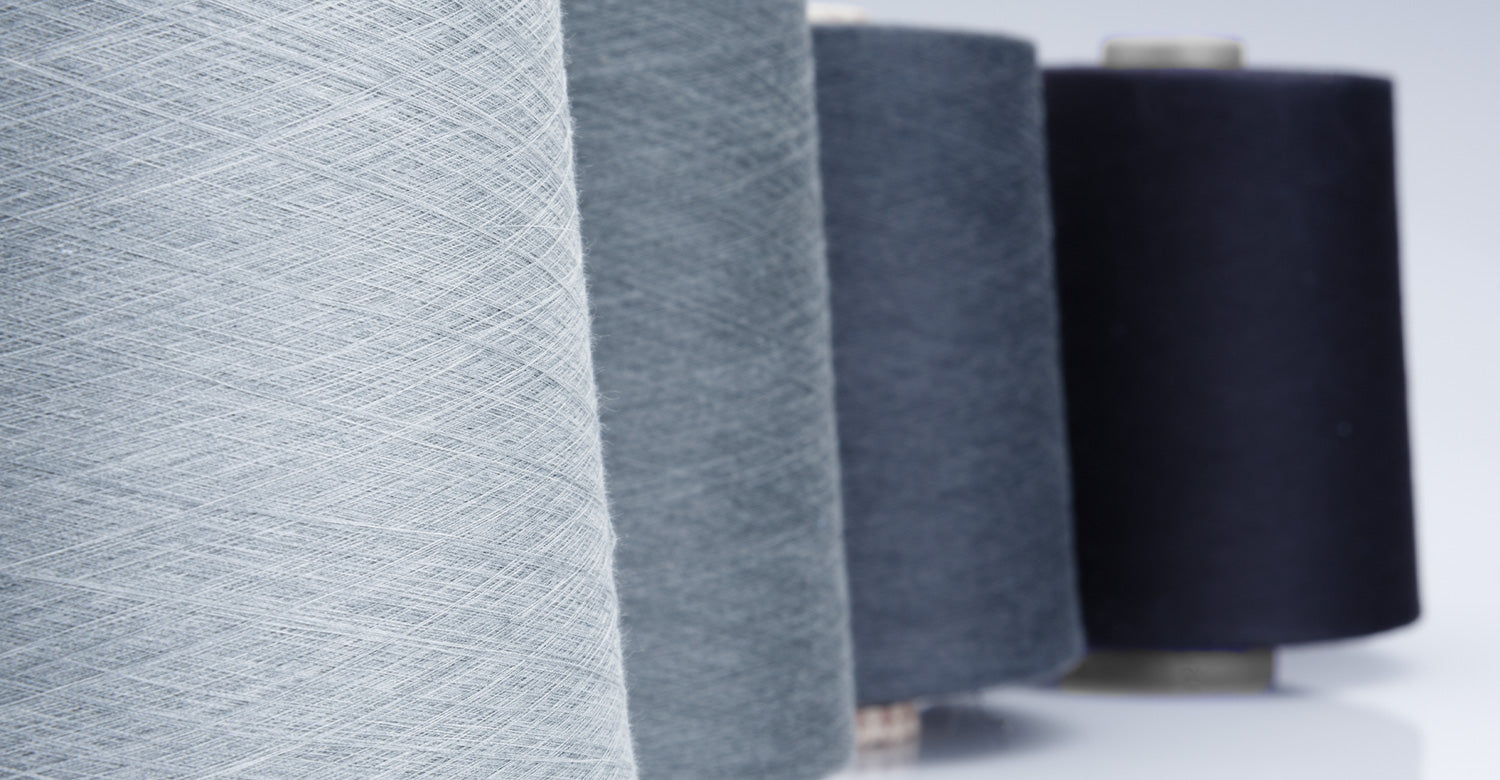 Fine yarn cones arranged from pale grey to deep navy